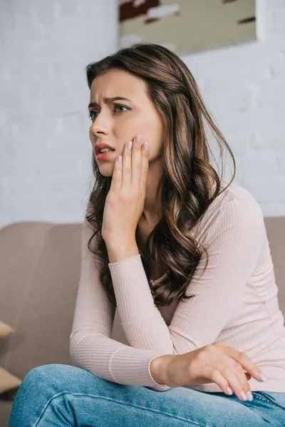 woman holding her mouth in tooth pain